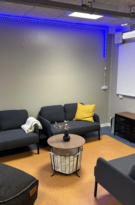 Sofagruppe med bord i midten samt projekter op af en væg